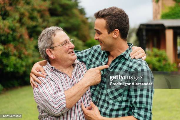 pai e filho adulto celebrando em seu quintal - camisa xadrez - fotografias e filmes do acervo