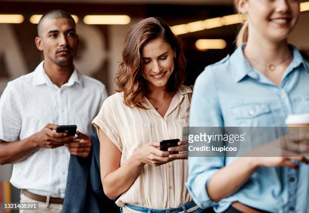 shot of a young businesswoman using a smartphone while waiting in line in a modern office - waiting phone stock pictures, royalty-free photos & images