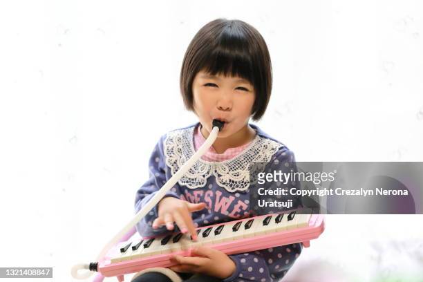 cute little girl happily playing keyboard harmonica - harmonica stock pictures, royalty-free photos & images