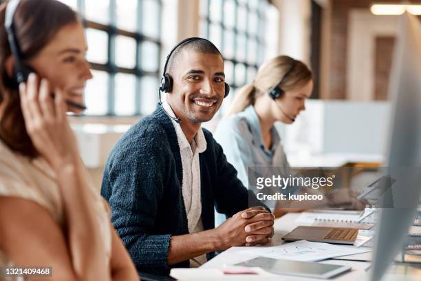 schuss eines jungen mannes mit headset und computer in einem modernen büro - callcenter stock-fotos und bilder