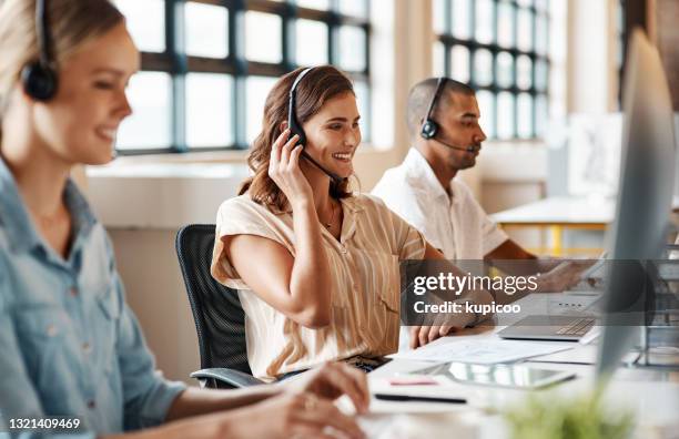 ontsproten van een jonge vrouw die een hoofdtelefoon en computer in een modern bureau met behulp van - serving stockfoto's en -beelden