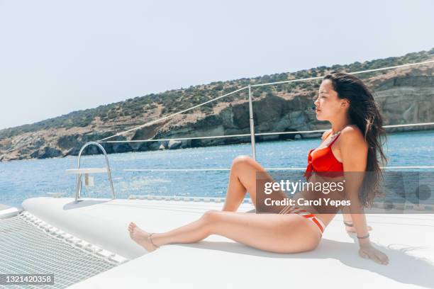 hispanic female in red bikini sunbathing on  sailboat during holidays - shade sail stock pictures, royalty-free photos & images