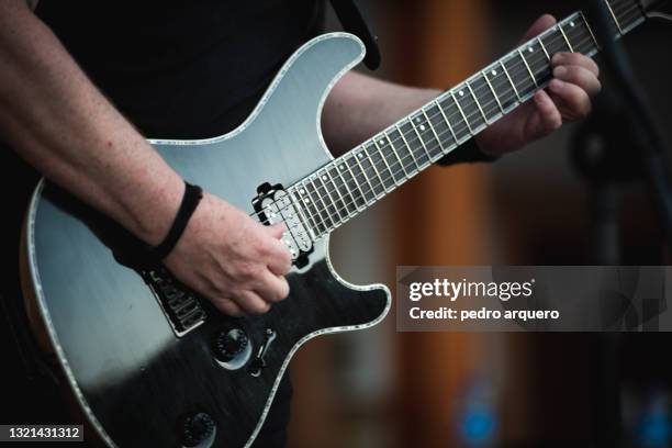 hands playing a chord on an electric guitar - elektrogitarre stock-fotos und bilder