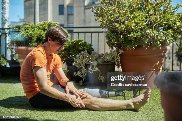 caucasian sportsman with physical disability massaging knee - quadriceps muscle stock pictures, royalty-free photos & images