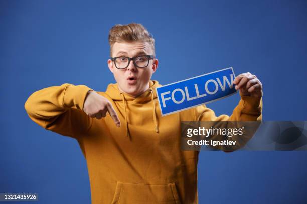the blogger holds a "follow me" sign and asks people to subscribe to his channel and like it. - follow me to man stock pictures, royalty-free photos & images