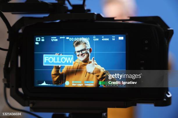 a close-up photo of the camera, on the display of which you can see the image that it takes. the camera shoots a vlogger who is holding a "follow" sign. - backstage sign stock pictures, royalty-free photos & images