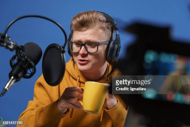 a vlogger drinks coffee from a yellow cup during a live stream to the internet. - content stock pictures, royalty-free photos & images