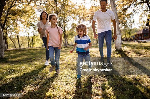 Happy Kids Running Away From Their Parents In The Park High-Res Stock