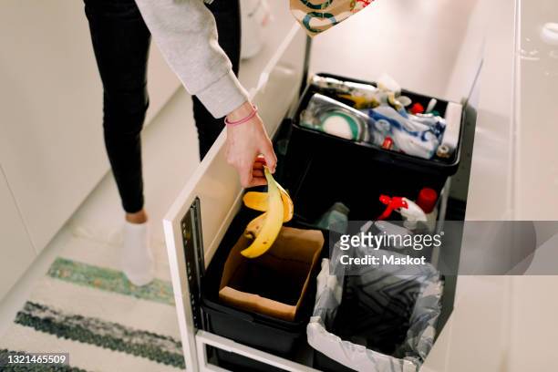 girl throwing banana peel in garbage can at home - バナナの皮 ストックフォトと画像