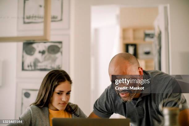 father and daughter using laptop in kitchen at home - parental control stock-fotos und bilder