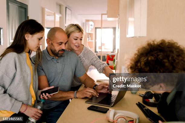 woman discussing with man over laptop by daughter at kitchen island - mother with daughters 12 16 stock-fotos und bilder