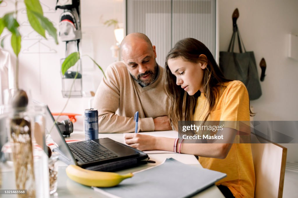 Father assisting daughter doing homework at home