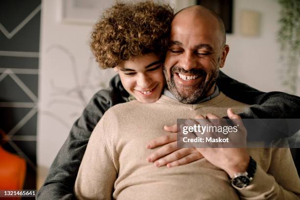 portrait of smiling boy hugging cheerful father from behind - dad son stockfoto's en -beelden