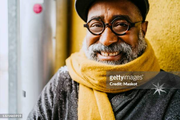portrait of smiling senior man wearing yellow scarf - old hipster stock-fotos und bilder