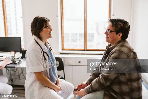 smiling female doctor and male patient discussing while consulting at medical clinic - doctor and patient talking imagens e fotografias de stock