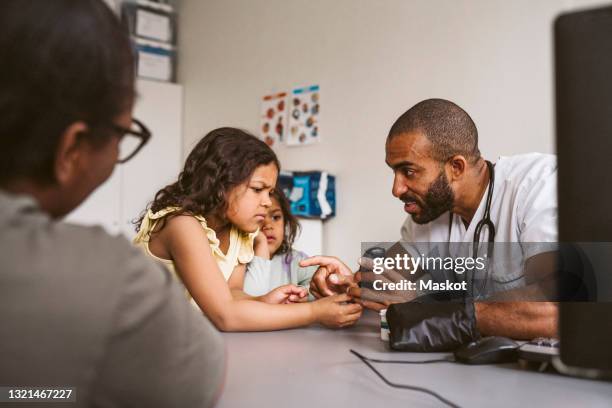 male doctor showing glaucometer to girl in medical clinic - glaucometer stockfoto's en -beelden