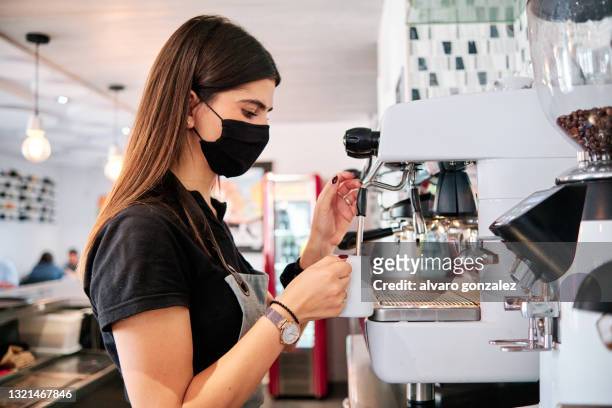 young waiter with protective mask using a coffee machine - waitress stock pictures, royalty-free photos & images
