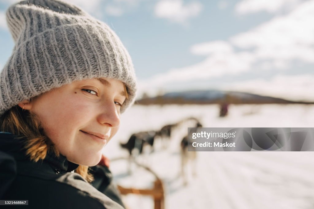 Portrait of teenage girl wearing knit hat doing dogsledding during winter
