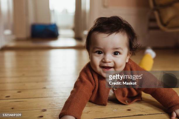 portrait of smiling male toddler lying on floor at home - 這う ストックフォトと画像
