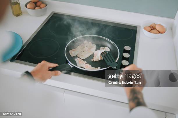 aziatisch chinees hoger mensen kokend bacon op kookplaat in keuken tijdens ochtend die voor breakfas voorbereidingen treft - braadpan stockfoto's en -beelden