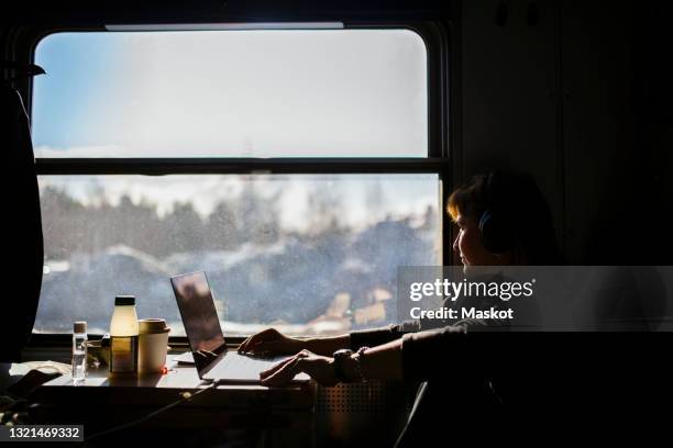 female entrepreneur looking through window while traveling in train - train window stock pictures, royalty-free photos & images