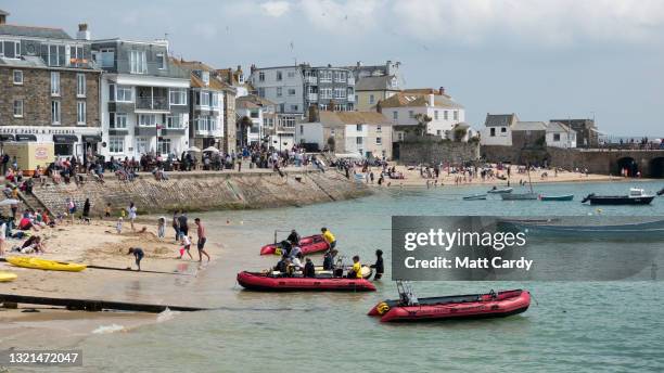 Large crowds of people gather around the harbour at the popular tourist seaside town of St Ives, close to The Carbis Bay Estate hotel and beach,...
