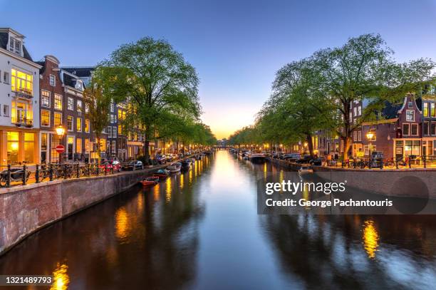 beautiful canal in amsterdam with city lights turned on - canal stock-fotos und bilder