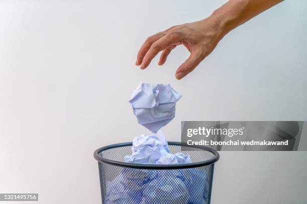 man hand throwing crumpled paper to the basket. - white trash stock-fotos und bilder