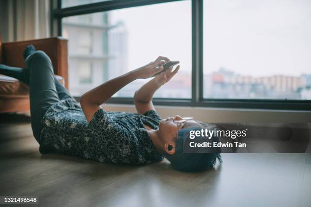 asiatische chinesische teenager mit smartphone im wohnzimmer während des wochenendes musik hören liegen - young boy enjoying music stock-fotos und bilder