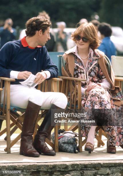 Prince Charles, Prince of Wales, wearing a navy blue Ralph Lauren jumper with jodhpurs and riding boots, sits next to his girlfriend and sister of...