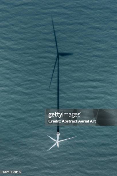 aerial shot looking down on an offshore wind turbine and its shadow, england, united kingdom - wind turbine aerial stock pictures, royalty-free photos & images