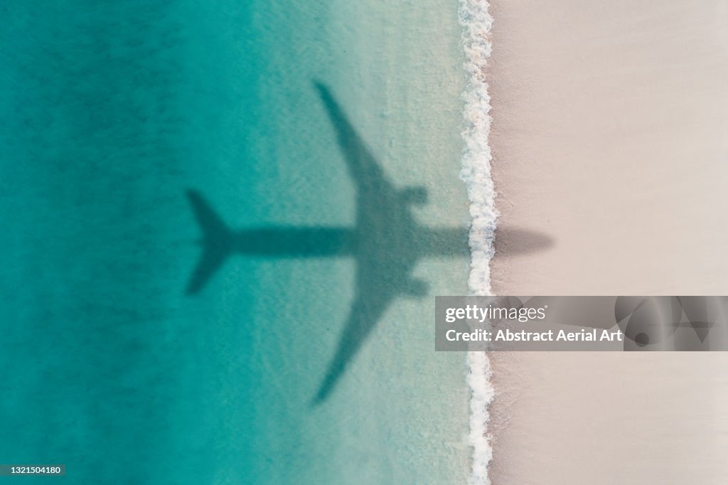 Aerial shot showing an aircraft shadow flying over an idyllic beach scene, Barbados