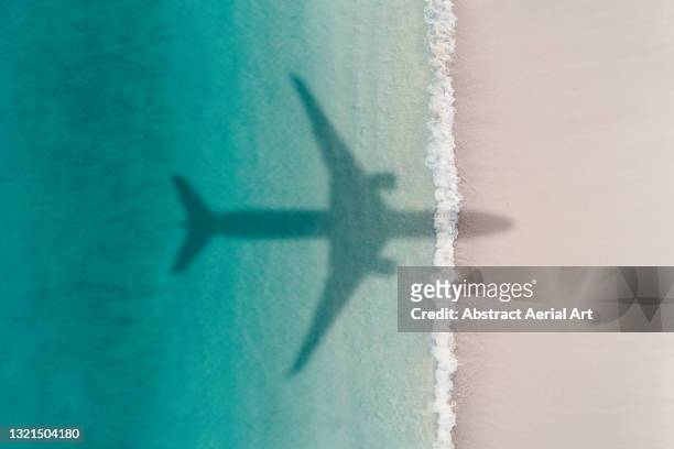 aerial shot showing an aircraft shadow flying over an idyllic beach scene, barbados - reise stock-fotos und bilder