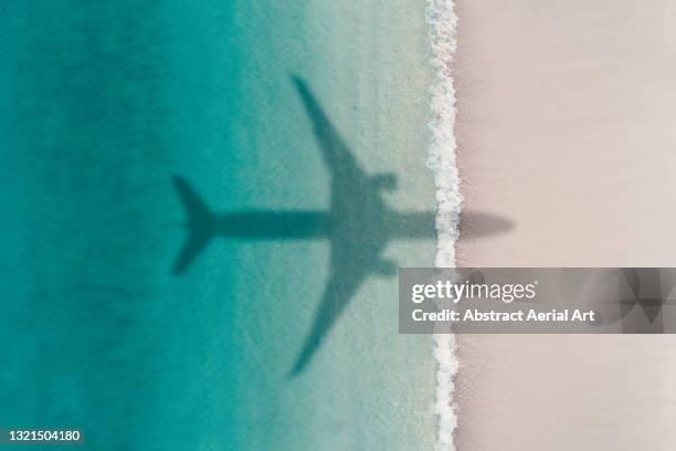 aerial shot showing an aircraft shadow flying over an idyllic beach scene, barbados - avion plage photos et images de collection