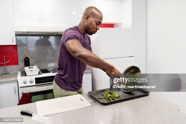 mature african-american man cooking meal in his kitchen. - shaved asparagus stock pictures, royalty-free photos & images