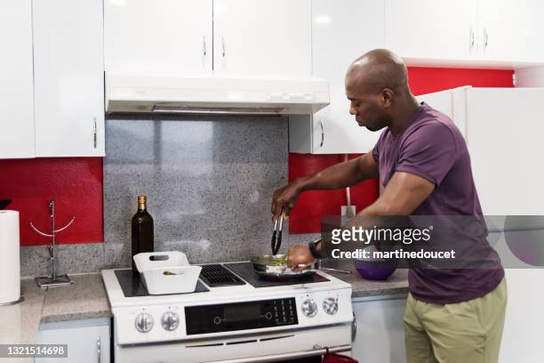 mature african-american man cooking meal in his kitchen. - shaved asparagus stock pictures, royalty-free photos & images