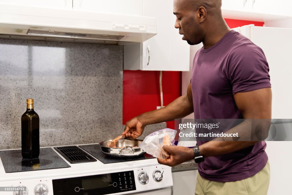 Mature African-American man cooking meal in his kitchen.