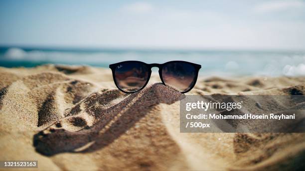 close-up of sunglasses on sand at beach - sunglasses reflection stock pictures, royalty-free photos & images