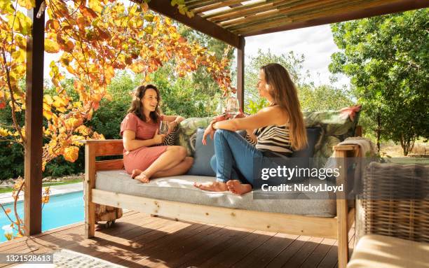 due donne sedute in un patio e che parlano di bicchieri di vino - garden furniture foto e immagini stock