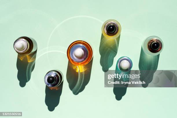 trendy beauty concept of facial serums, natural essential oil in cosmetic bottles with dropper and bright sunligth shadow on green mint turquoise background. - laboratoriumglas stockfoto's en -beelden