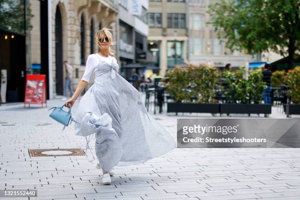 Influencer Gitta Banko wearing a pastel blue maxi dress with floral print and leg slit by Alanui, a white t-shirt by Closed, white clogs by Chanel, a...