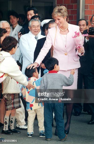 Diana, Princess of Wales, wearing a pale pink suit with a pearl necklace and black heels, greets children as she departs after visiting The National...