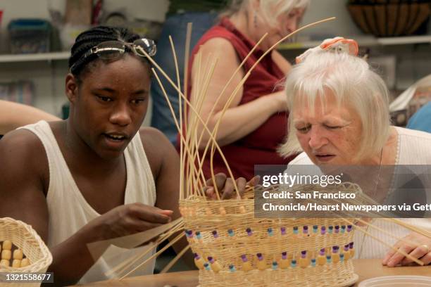 Jessica Gonzalez , a head counselor from Oakland, helping Marvelle Giacobbi , from Lafayette, with basket weaving at the Enchanted Hills Camp, a...
