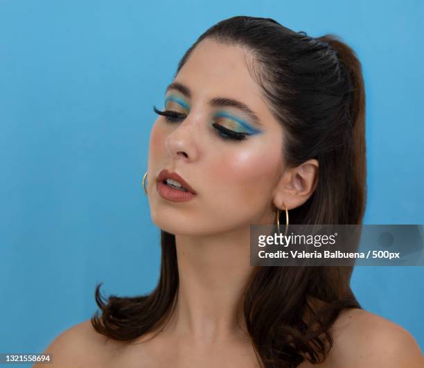close-up of young woman against blue background - editorial woman stock pictures, royalty-free photos & images