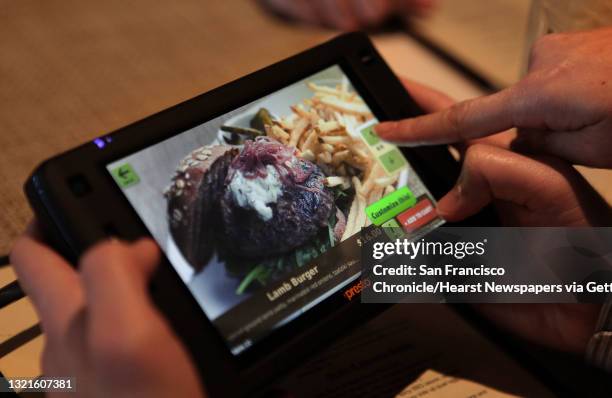Patrons scrolling a new tablet that restaurants can put at every table for do-it-yourself ordering and paying the bill at Calafia in Palo Alto,...