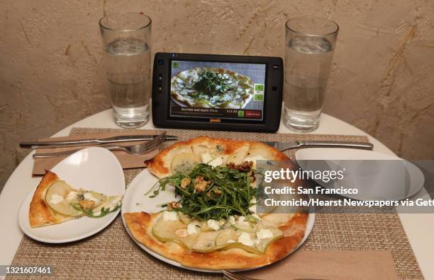 Burrata and apple pizza next to a new tablet that restaurants can put at every table for do-it-yourself ordering and paying the bill at Calafia in...