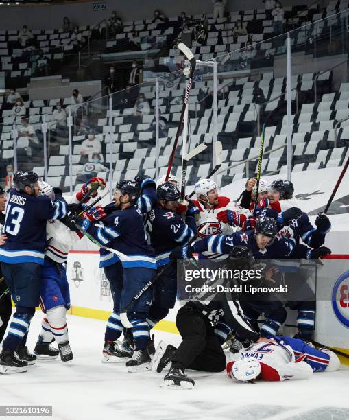 Jake Evans of the Montreal Canadiens is left injured after scoring a third period empty net goal and then checked hard by Mark Scheifele of the...