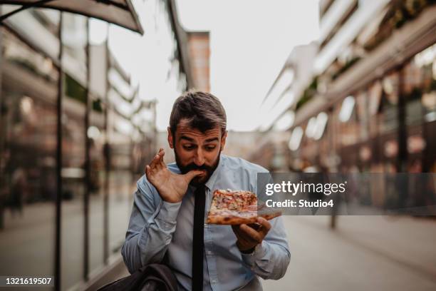 enjoying a walking pizza bite - comer pizza imagens e fotografias de stock