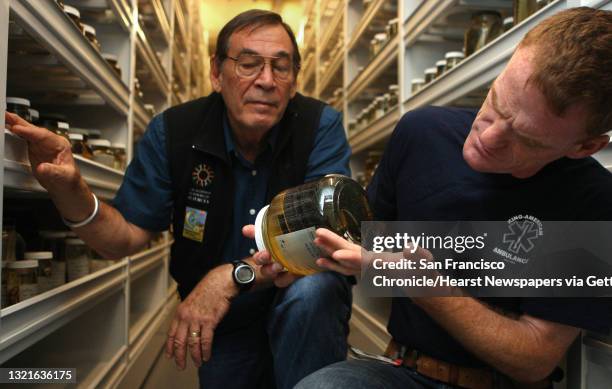 Curator and chair of herpetology Bob Drewes and Dr. Matt Lewin look at a forest cobra in the herpetology collections room at the California Academy...