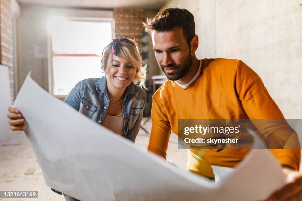 gelukkig paar dat plannen analyseert bij hun het renoveren flat. - renovatie stockfoto's en -beelden